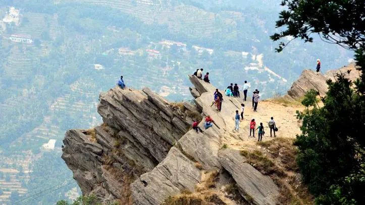 Perched high above the valleys of Mukteshwar, this dramatic rocky viewpoint offers breathtaking panoramic views of the surrounding Himalayan landscape. Visitors can be seen exploring the rugged cliff edges, enjoying the fresh mountain air and stunning scenery. The unique rock formations, lush green forests, and terraced hills in the background make this spot a perfect destination for nature lovers, photographers, and adventure seekers. The serene atmosphere and awe-inspiring vistas capture the true essence of the Mukteshwar Nature Trail, one of Uttarakhand