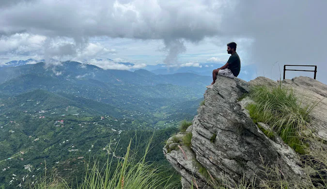 Capture the Beauty of Mukteshwar Like a Pro with lush green hills, dramatic clouds, and rain-covered Himalayan mountains.